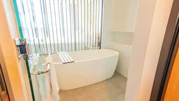 A modern bathroom with a freestanding bathtub, a glass shower enclosure, and a tiled floor.