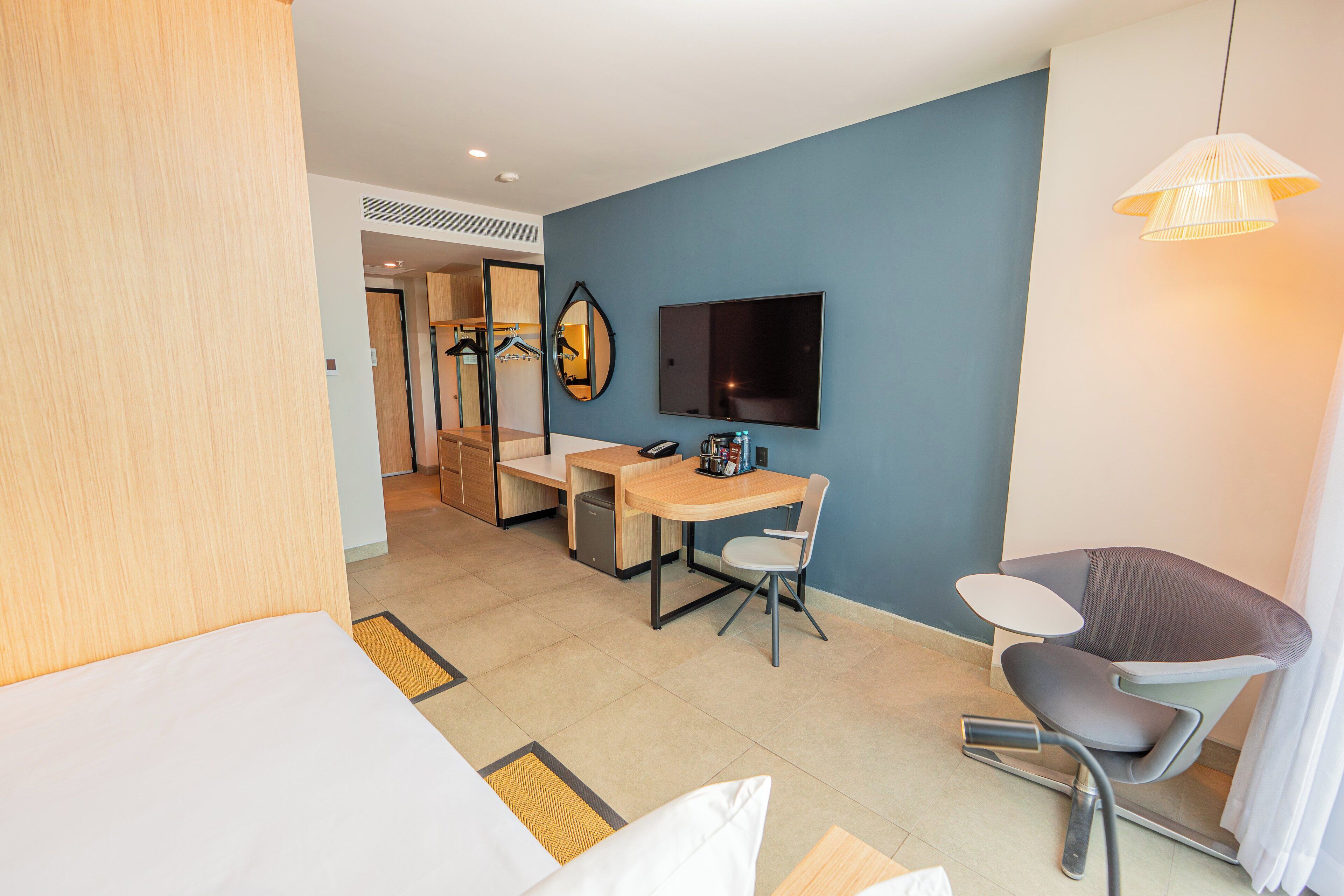 Ein Hotelzimmer mit Bett, Schreibtisch, Stuhl, Fernseher und Duschbereich.