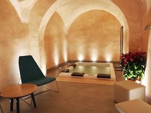 Een spa ruimte met een massagetafel, een massagestoel en een klein tafeltje.