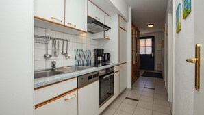 Una cocina moderna con armarios blancos, un lavamanos de acero inoxidable y un horno empotrado.
