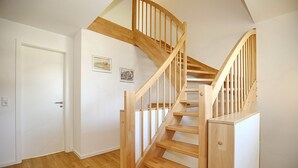 Un escalier avec des marches et une rampe en bois, menant à l’étage supérieur.