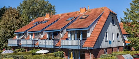 A multi-story building with a red-tiled roof, balconies, and a brick facade.