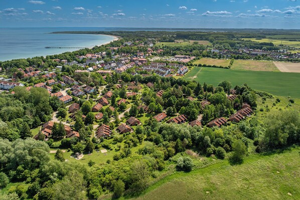 An aerial view of a residential area with houses, green spaces, and a coastline. - Urlauberdorf Haus 38b (Ostseebad Boltenhagen)
