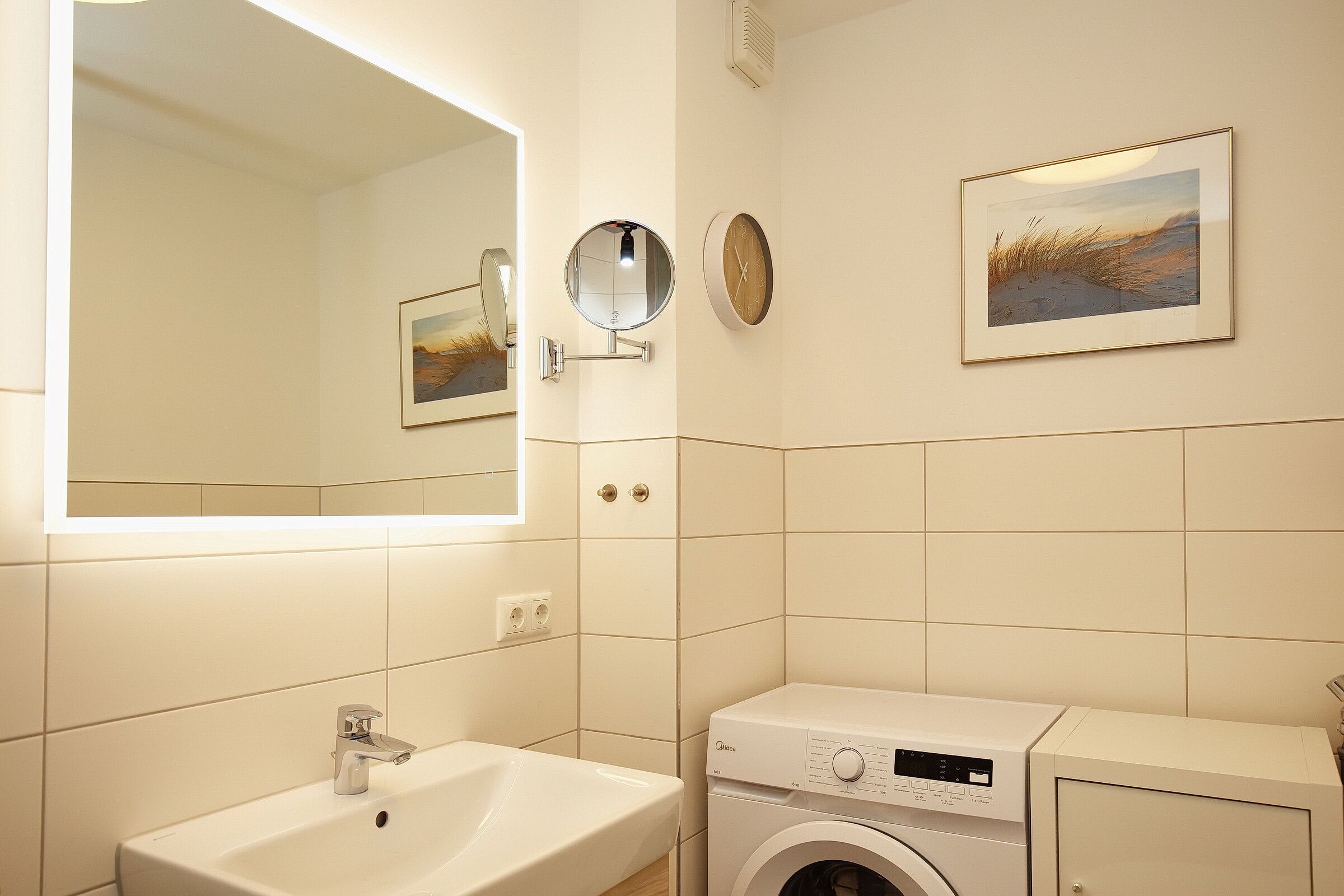 Un baño con lavabo, espejo, reloj y lavadora.