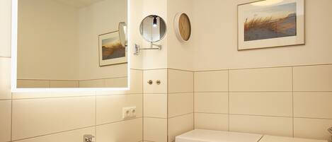 Un baño con lavabo, espejo, reloj y lavadora.