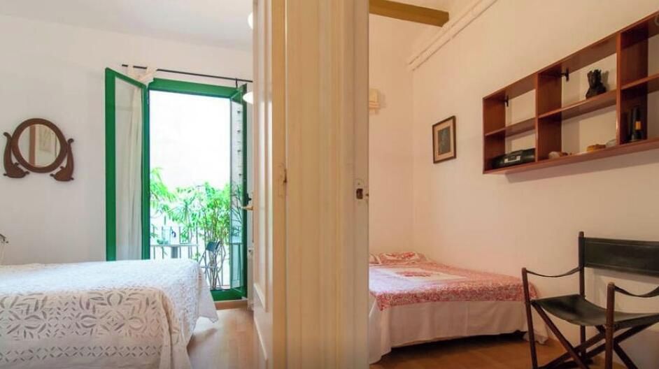 Ein Schlafzimmer mit einem Bett, einem Sessel und einem Regal mit Gegenständen.