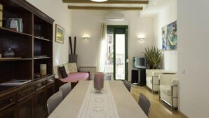 A dining area with a table set for four, a bookshelf, a television, and a plant.
