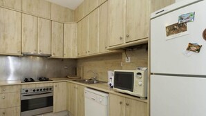 A kitchen with wooden cabinets, a stove, a microwave, and a refrigerator.