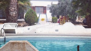 Ein Poolbereich mit einem Gebäude im Hintergrund, umgeben von Palmen und einer Schaukel.