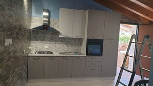 A kitchen with a gas stove, oven, and white cabinets. - Villa Marisa - Appartamento Blu (Borgo Bonsignore)