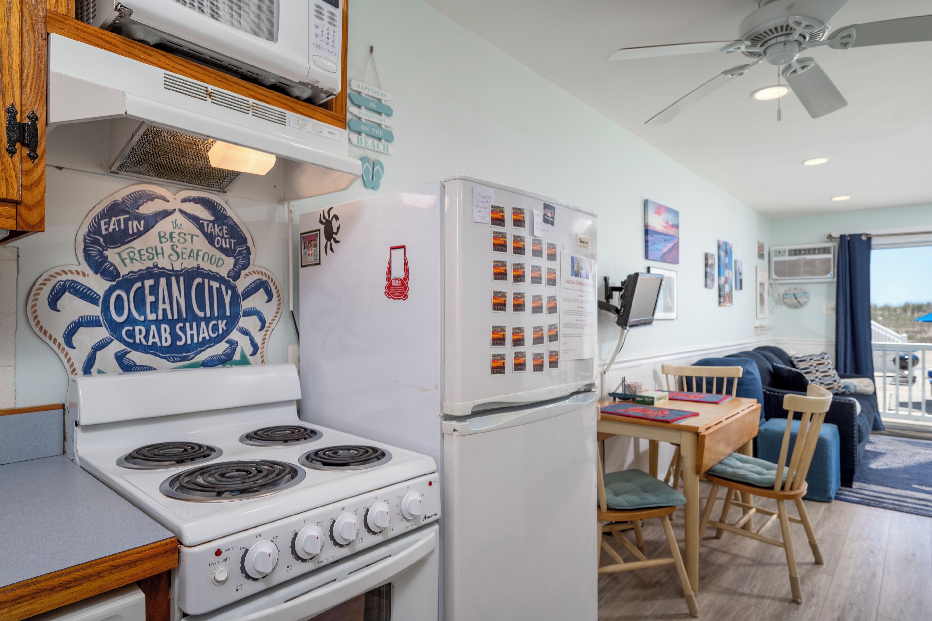 A kitchen with a stove, refrigerator, and dining area with chairs and a table.