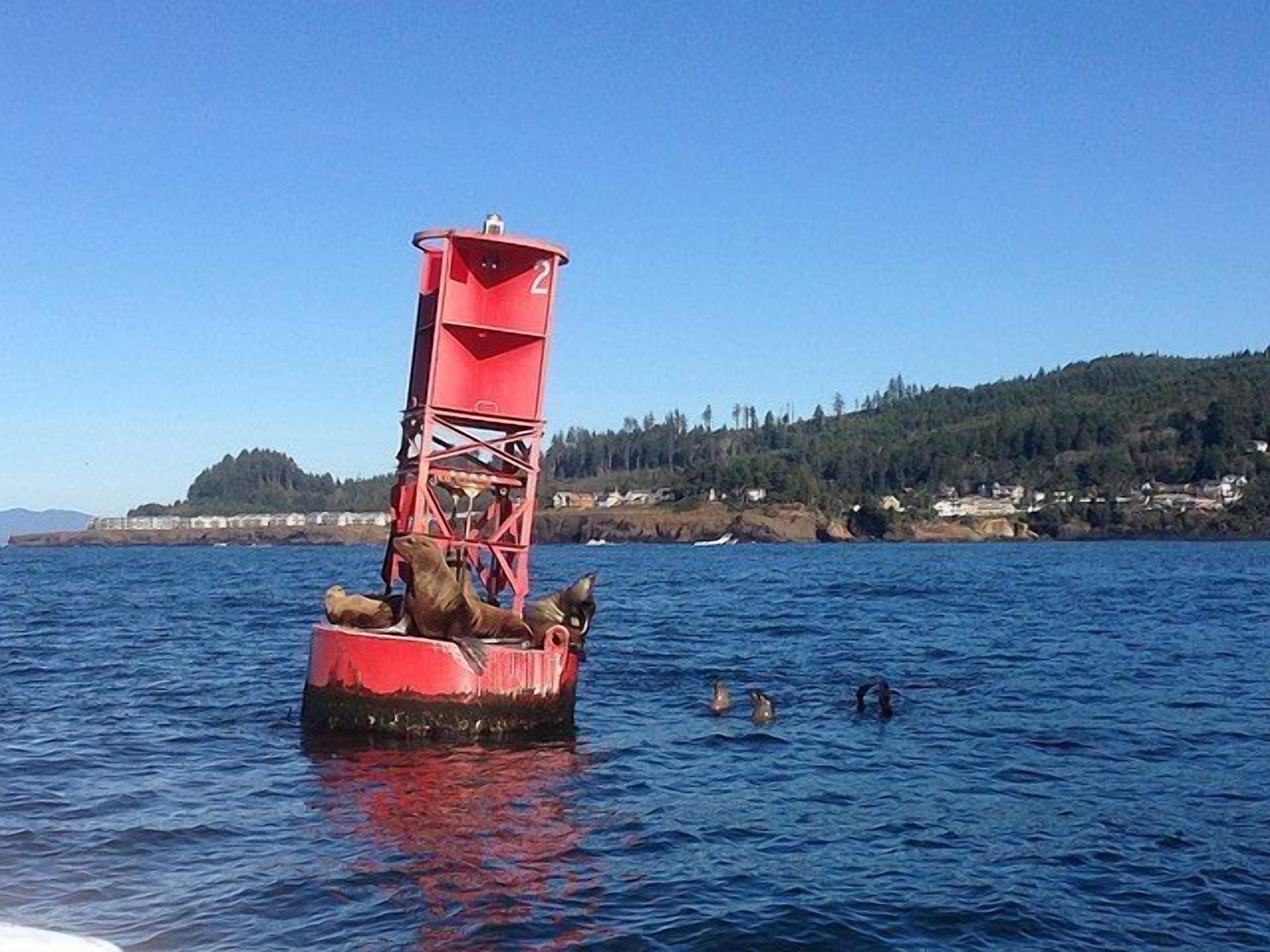A red buoy with a platform and a person standing on it in the water.