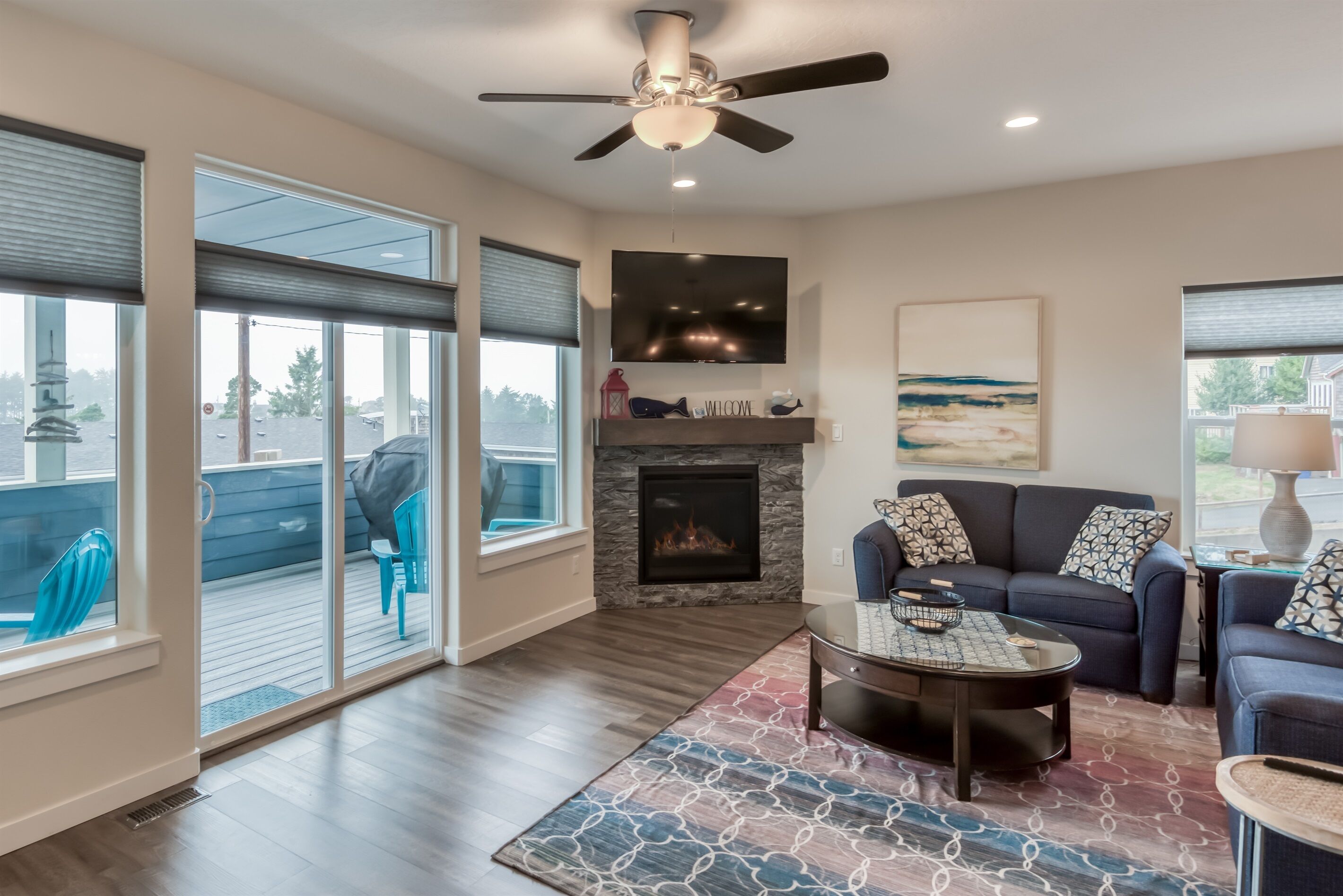 A modern living room with a fireplace, a ceiling fan, a large TV, and a sofa.