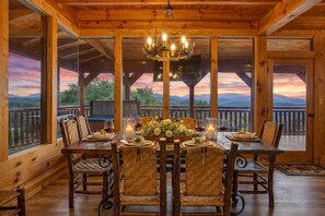 A wooden dining area with a table set for four, surrounded by large windows offering a scenic view.