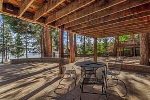 Eine Terrasse im Freien mit einer Holz-Pergola, Metallstühlen und einem Tisch.