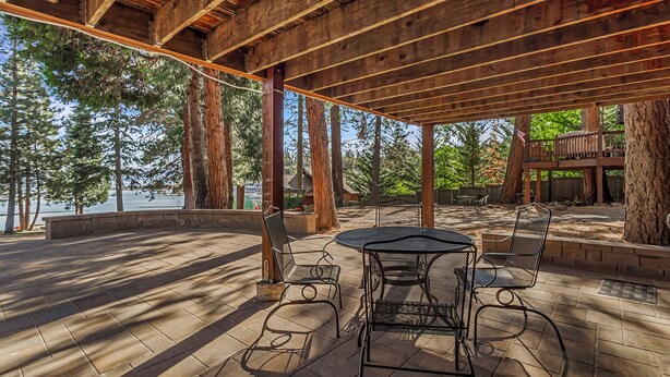 An outdoor patio with a wooden pergola, metal chairs, and a table.