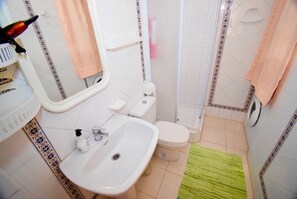 A bathroom with a sink, toilet, shower, and patterned tiles.