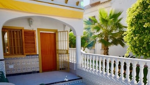 A two-story building with a balcony, a wooden door, and a tiled entrance. - Premium Holiday House  (Torrevieja)