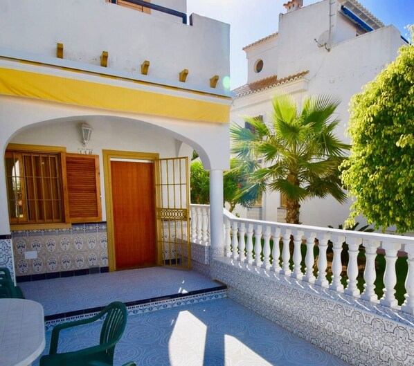 A two-story building with a balcony, a wooden door, and a tiled entrance.
