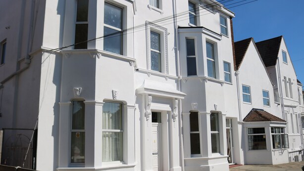 A row of white Victorian-style townhouses with bay windows and a small front porch. - Lennard House (Folkestone)