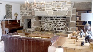A stone fireplace with a chandelier, a brown leather sofa, and a wooden coffee table in a living room. - La plage à pied - Plouhinec (Plouhinec)