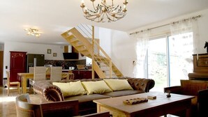 A spacious living room with a wooden staircase, a large sofa, and a dining area. - La plage à pied - Plouhinec (Plouhinec)