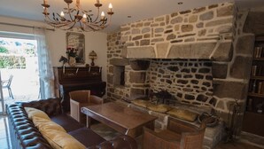 A cozy living room with a stone fireplace, leather sofa, and a dining table. - La plage à pied - Plouhinec (Plouhinec)