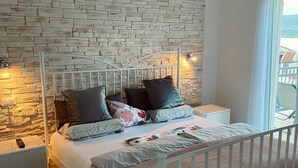 Een slaapkamer met een stenen muur, een metalen bed en uitzicht op een balkon.
