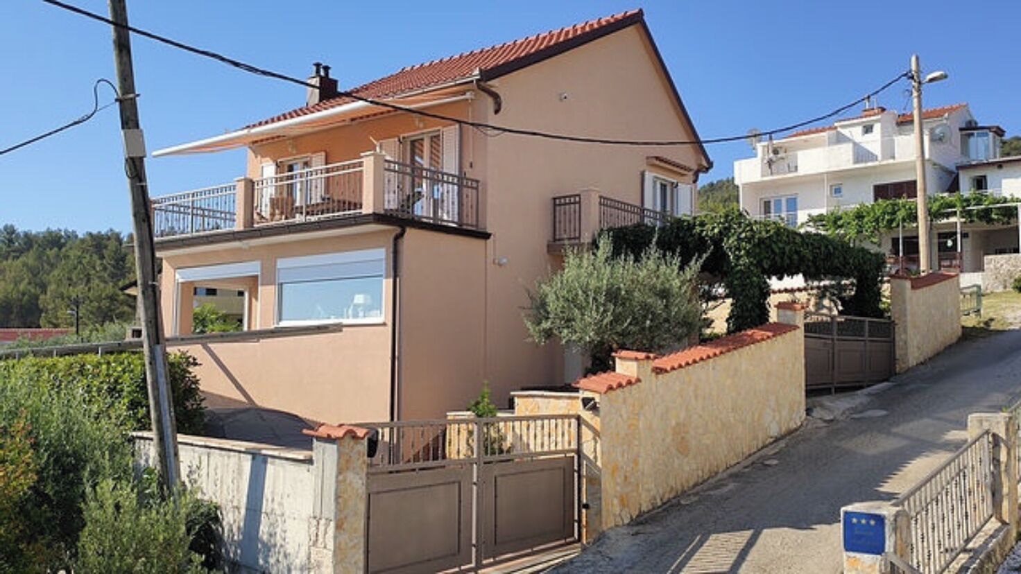 Un immeuble résidentiel à deux étages, doté d’un balcon, d’un garage et d’une entrée sécurisée par un portail.