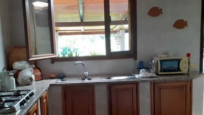 Une cuisine avec des meubles en bois, un évier, une cuisinière et une fenêtre donnant sur l’extérieur.