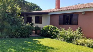 Une maison avec un toit recouvert de tuiles rouges, une cheminée et une pelouse bien entretenue.
