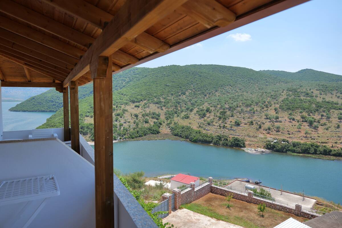 Vista desde un balcón cubierto hacia un lago y un paisaje montañoso.