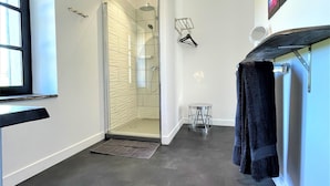 Ein modernes Badezimmer mit einer Glasdusche, einem Handtuchhalter und einem Spiegel.