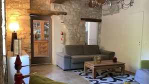 Ein gemütliches Wohnzimmer mit Steinwand, grauem Sofa, Holztisch und grünem Sessel.