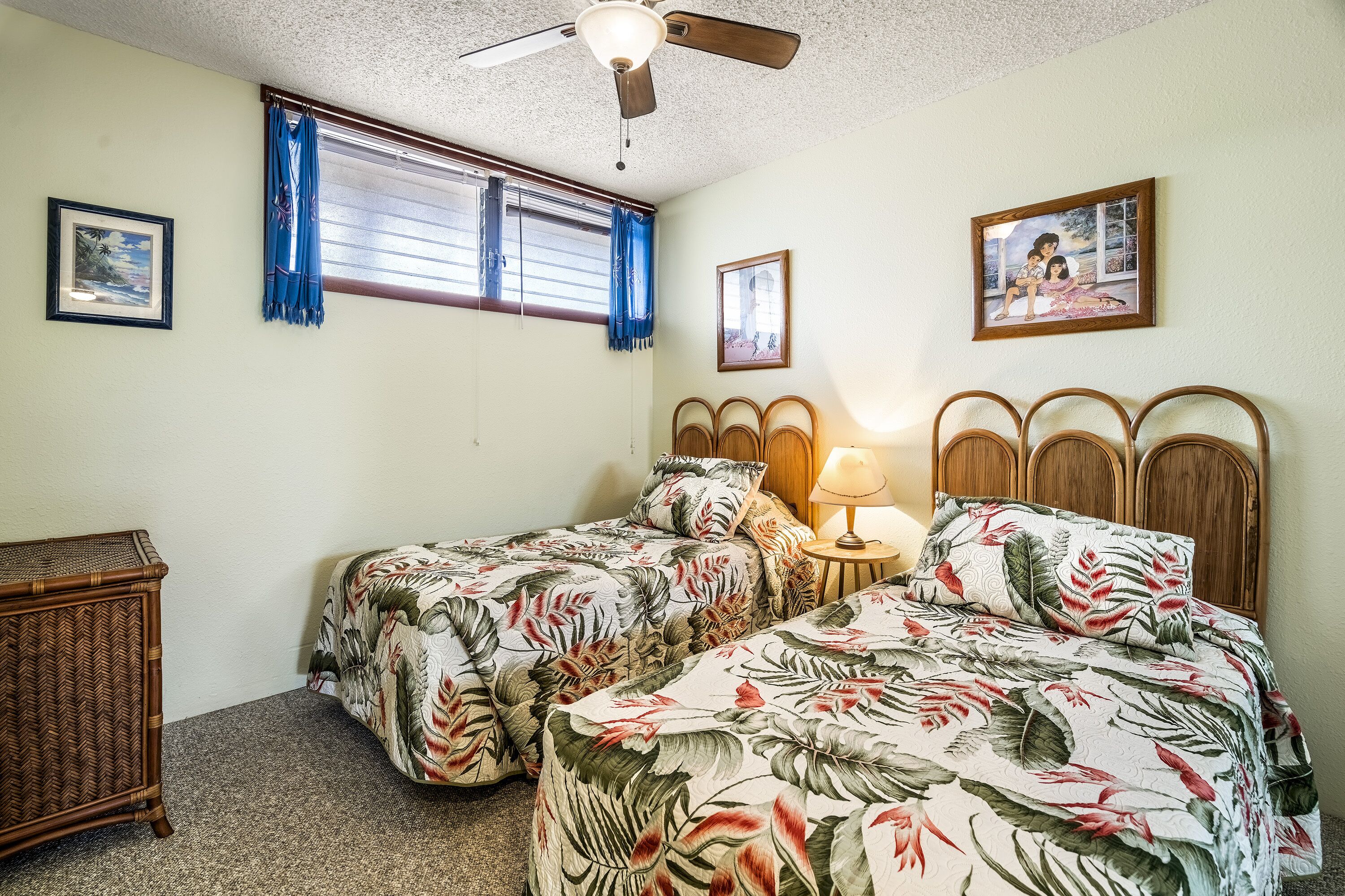 A bedroom with two single beds, a ceiling fan, and a window with curtains.