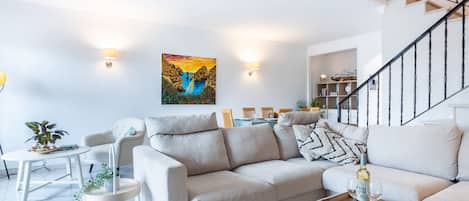A modern living room with a beige sofa, a wooden coffee table, and a painting on the wall.