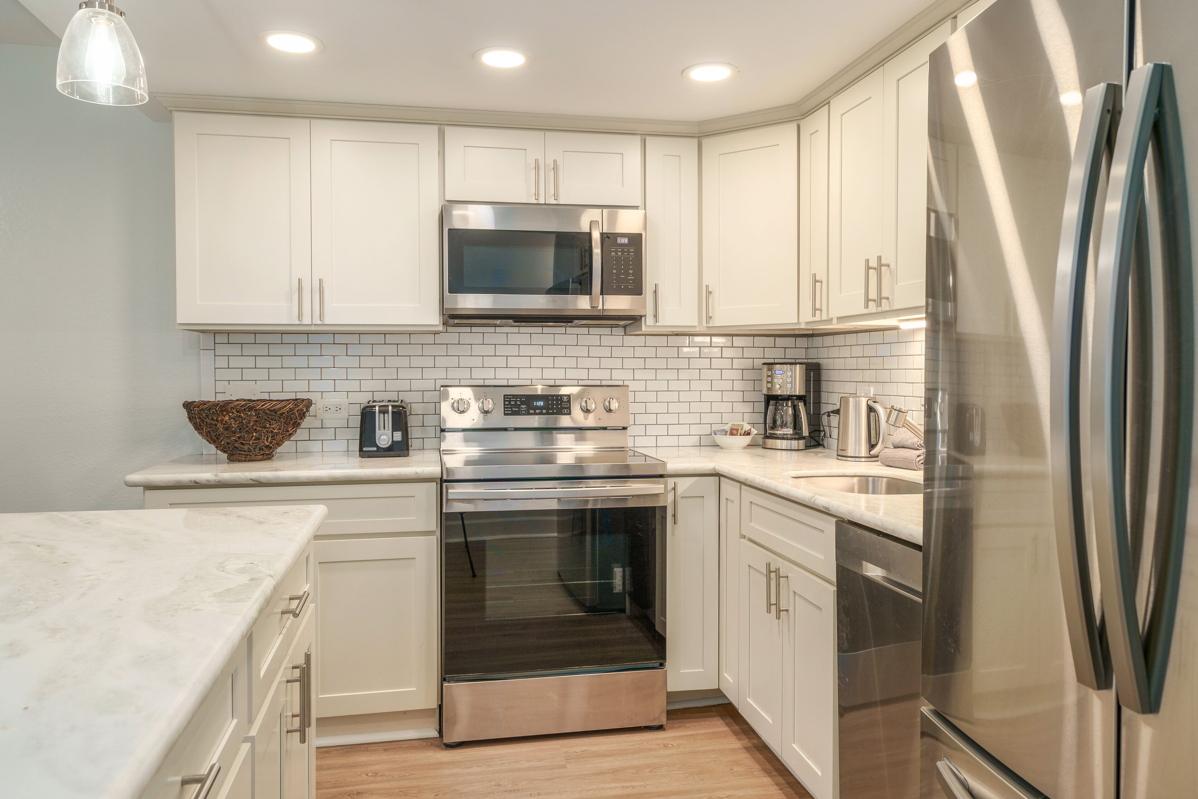 Una cocina moderna con armarios blancos, electrodomésticos de acero inoxidable y salpicadero de azulejos.
