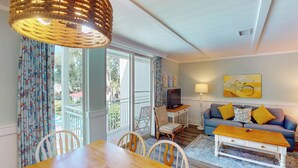 A cozy living room with a dining area, a sofa with cushions, a television, and a lamp.