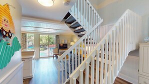 A spacious living area with a modern staircase, a dining area, and a view of the outdoors.