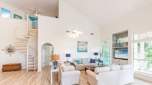 A spacious living area with a spiral staircase, a large sofa set, a flat-screen TV, and a view of the outdoors. - Walk to the Beach ~ Community Pool (Miramar Beach)