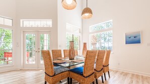 A dining area with a glass table, wicker chairs, and hanging wicker lamps. - Walk to the Beach ~ Community Pool (Miramar Beach)