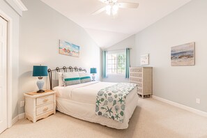 A bedroom with a bed, nightstand, dresser, and artwork on the walls. - Walk to the Beach ~ Community Pool (Miramar Beach)