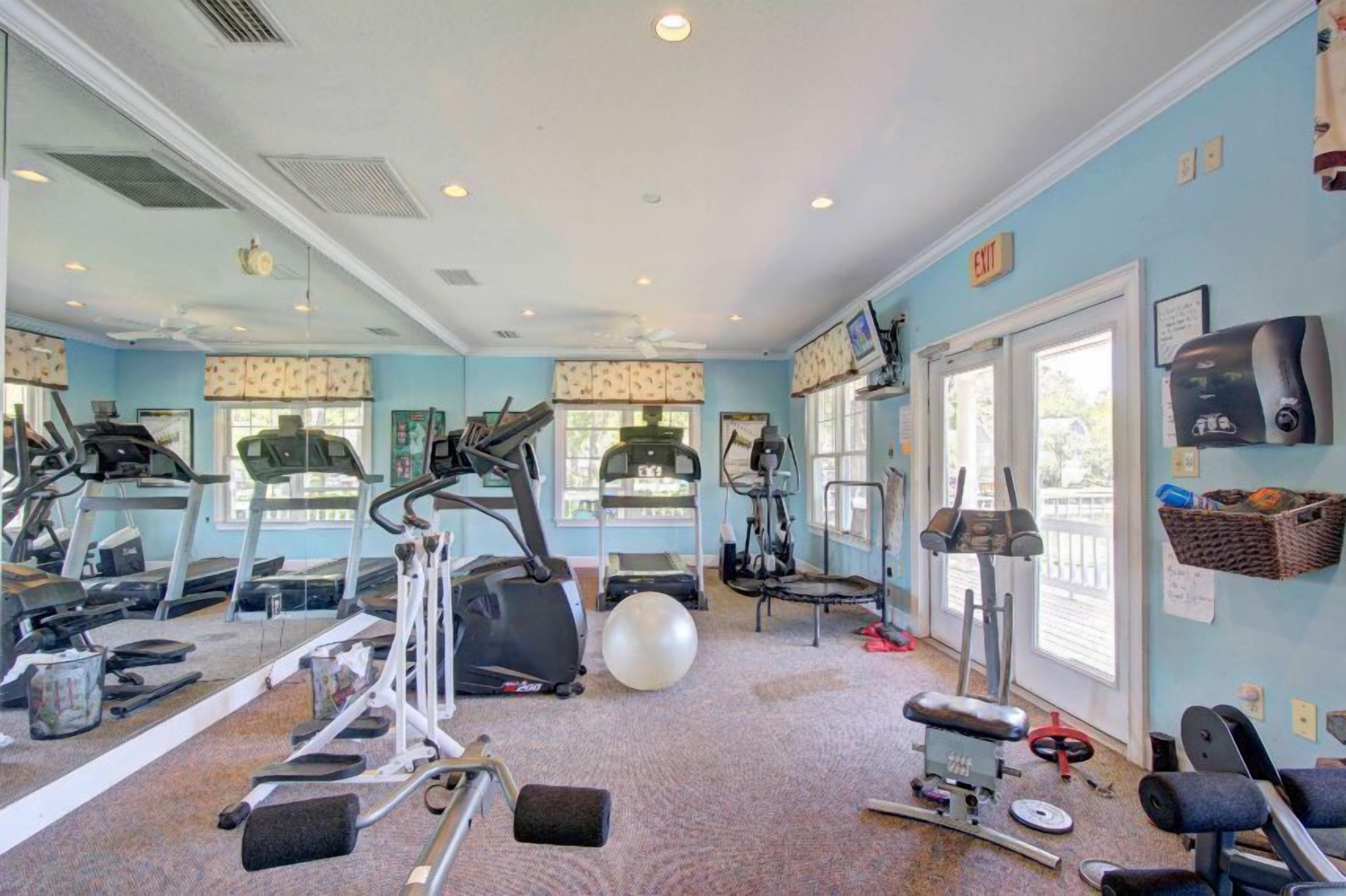 A gym with various exercise equipment, large windows, and a mirrored wall.