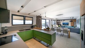 Eine moderne Küche mit grünen Schränken, einer großen Kochinsel und einem Essbereich mit Tisch und Stühlen.