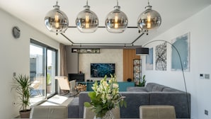 Ein modernes Wohnzimmer mit Esstisch, Sofa und großem Fenster.