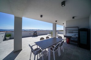 A rooftop patio with a table and chairs, a grill, and a view of the landscape. - Villa Oasis (Zadar)