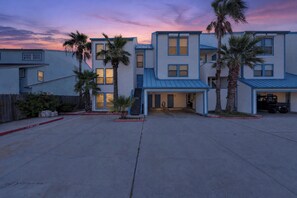 A multi-story residential building with a flat roof, multiple windows, and a fire lane marked on the pavement. - Waterfront Retreat | Pool, Hot Tub & Fishing Access (Corpus Christi)