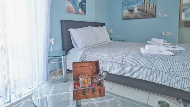 Une chambre à coucher avec un lit, une table en verre, une commode en bois et des œuvres d’art accrochées aux murs.