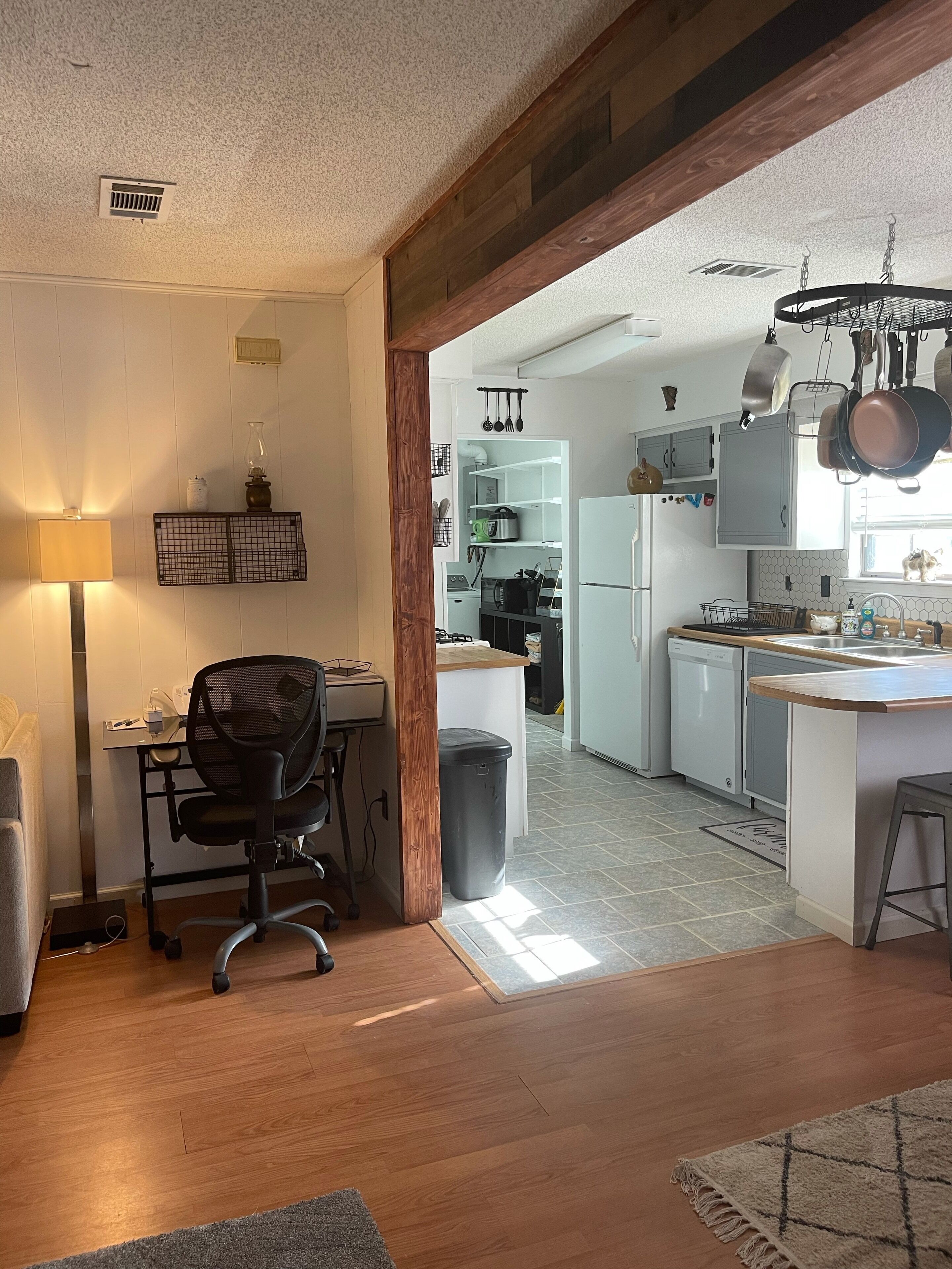 A modern kitchen with white cabinets, a built-in oven, and a hanging pot rack.