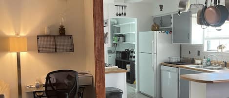 A modern kitchen with white cabinets, a built-in oven, and a hanging pot rack.